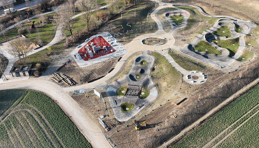 Fertiggestellte Multisportanlage in Dingolfing mit mehreren asphaltierten Pumptracks, Grünflächen und verbindenden Wegen